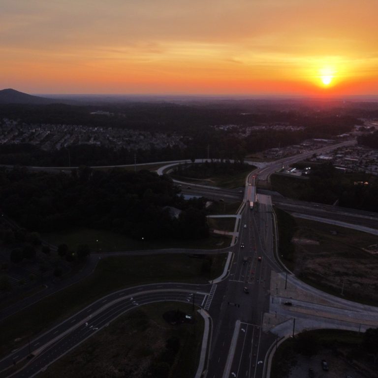 Aerial view of a highway 400 intersection exit 18 at sunset with a mountainous backdrop on browns bridge road.